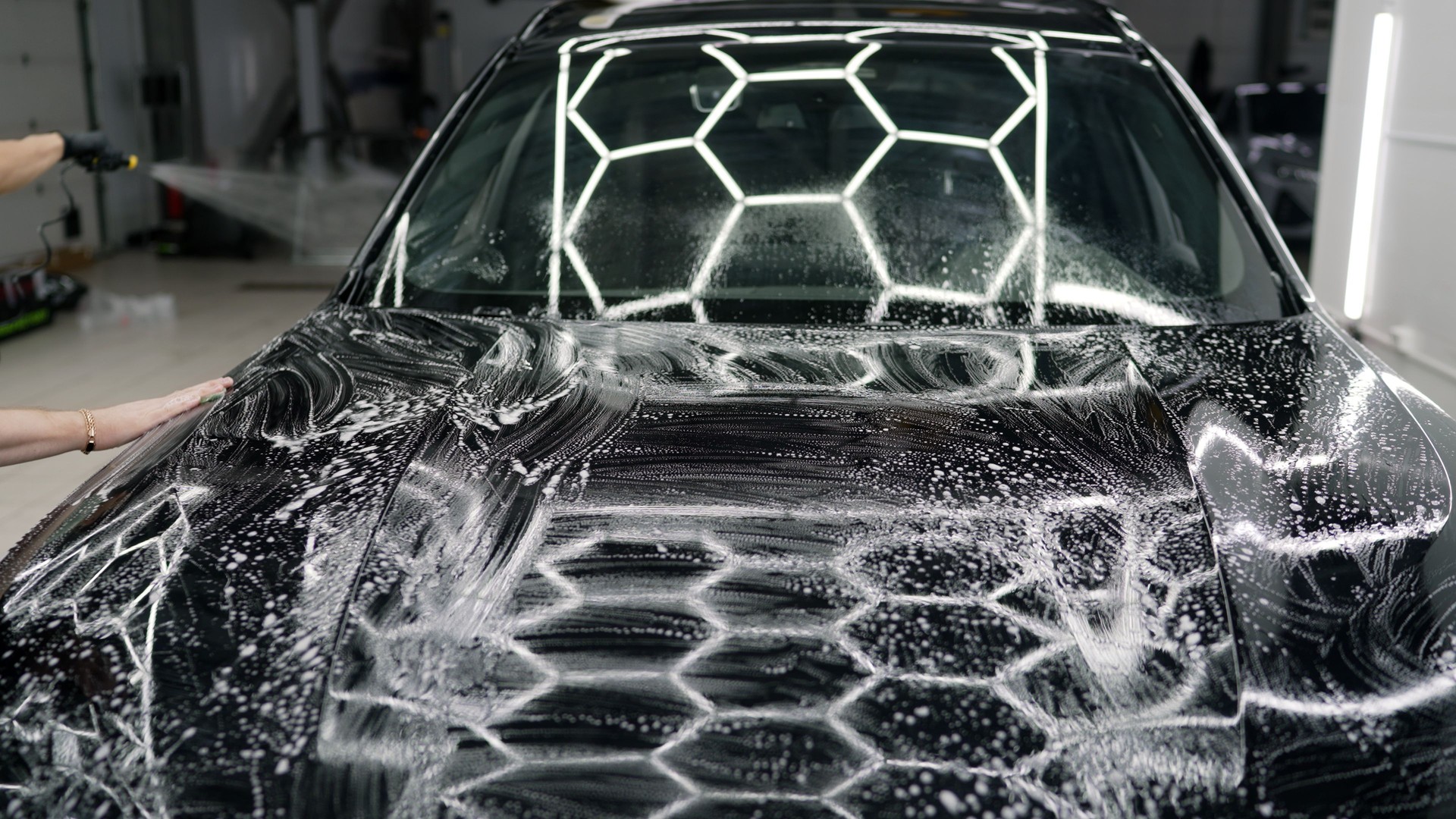 Car detailer applying soap on vehicle hood