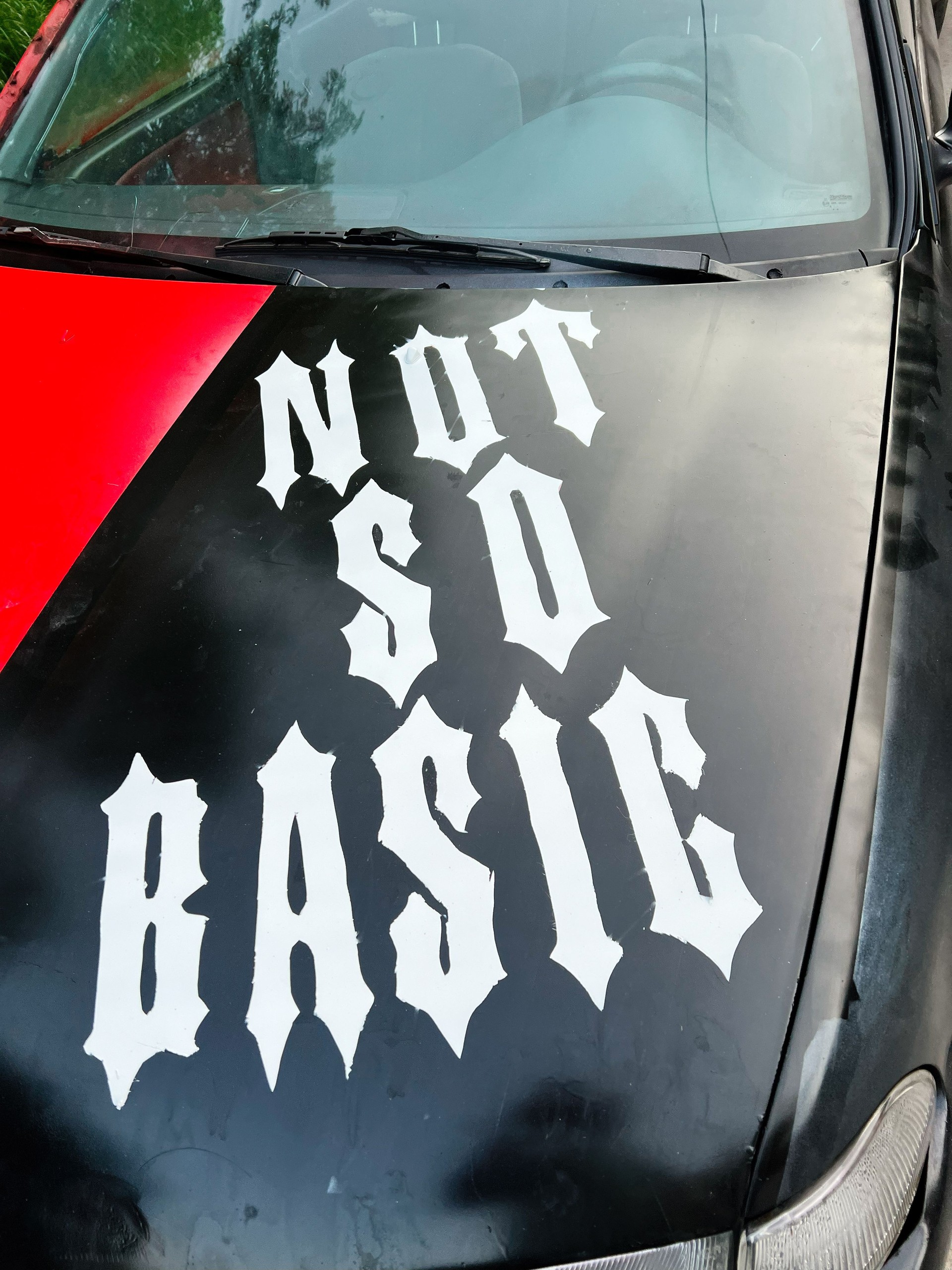 Car hood with bold 'Not so Basic' lettering in unique gothic style