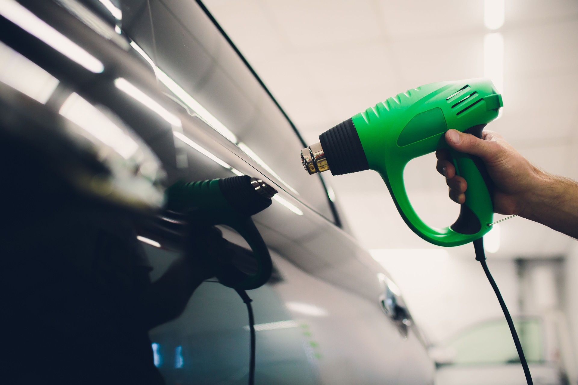 Master installs tint film for car with hairdryer. Concept protection car