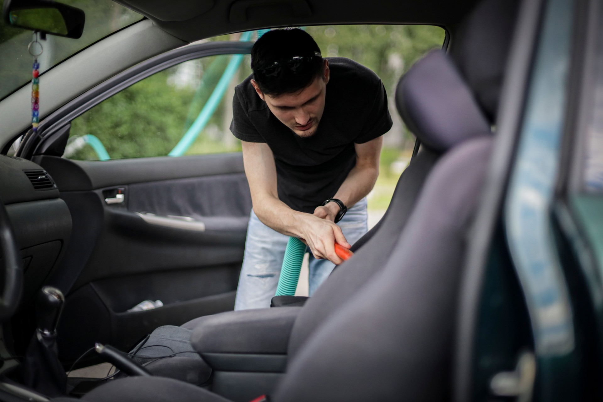 Caucasian man vacuuming a car at a gas station.